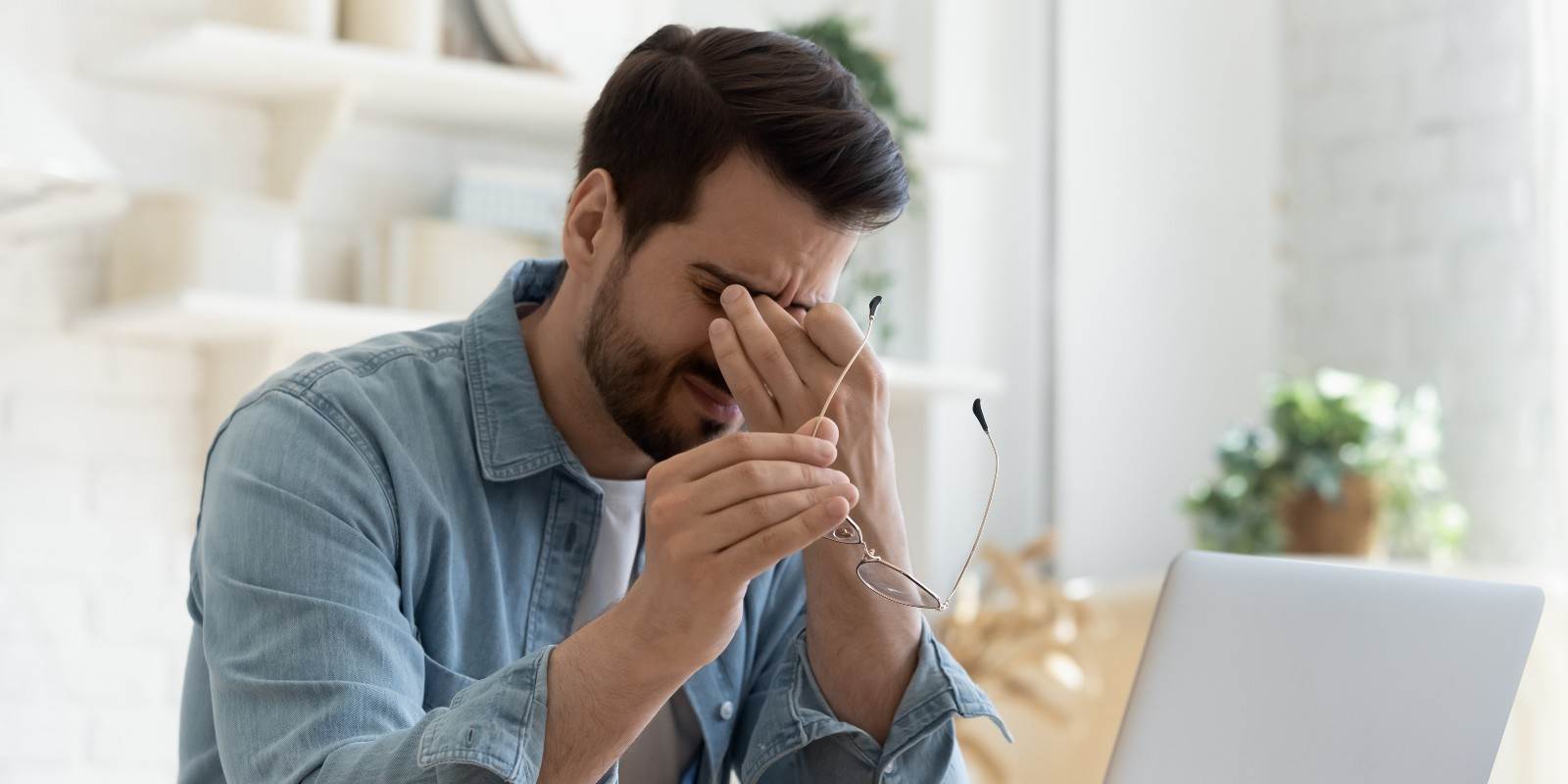 Podcast Müdigkeit - Mann sitzt vor dem Laptop und reibt sich die Augen