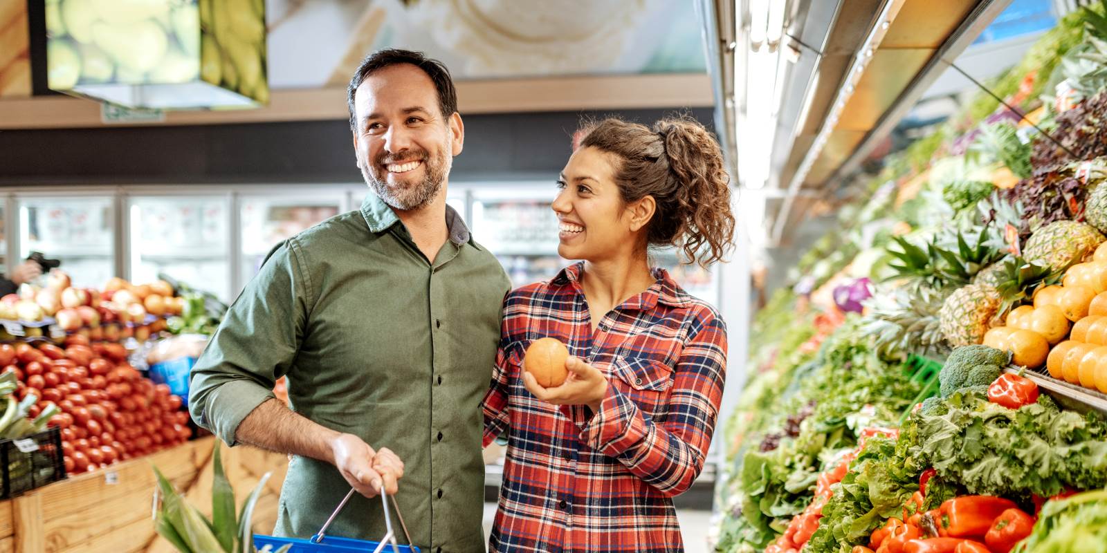 Ein Mann und eine Frau stehen vor dem Gemüseregal und lachen