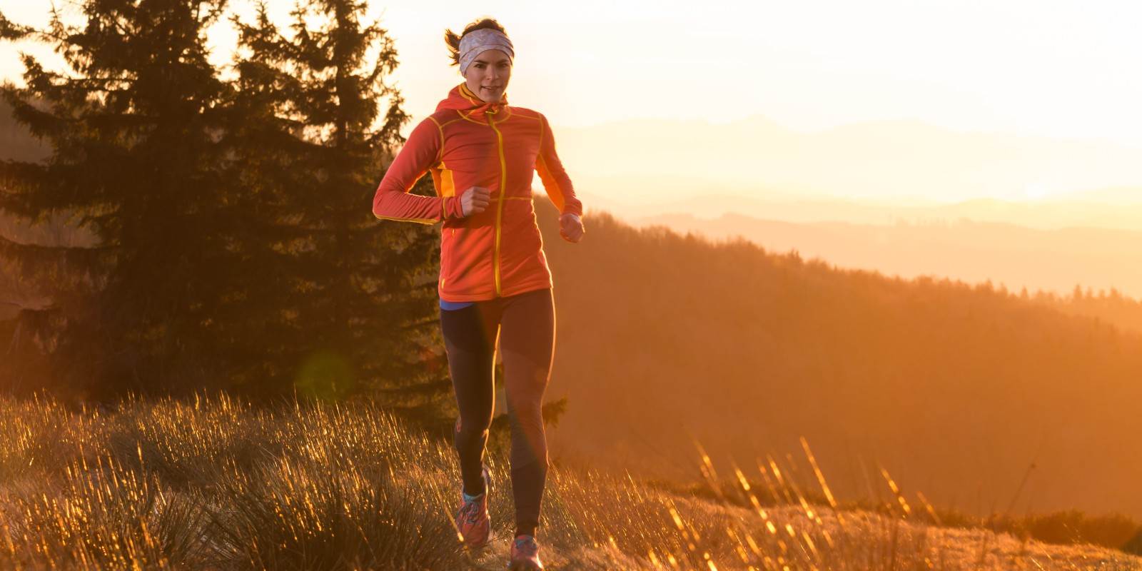 Sport junge Frau joggt bei Sonnenaufgang im Gegenlicht 