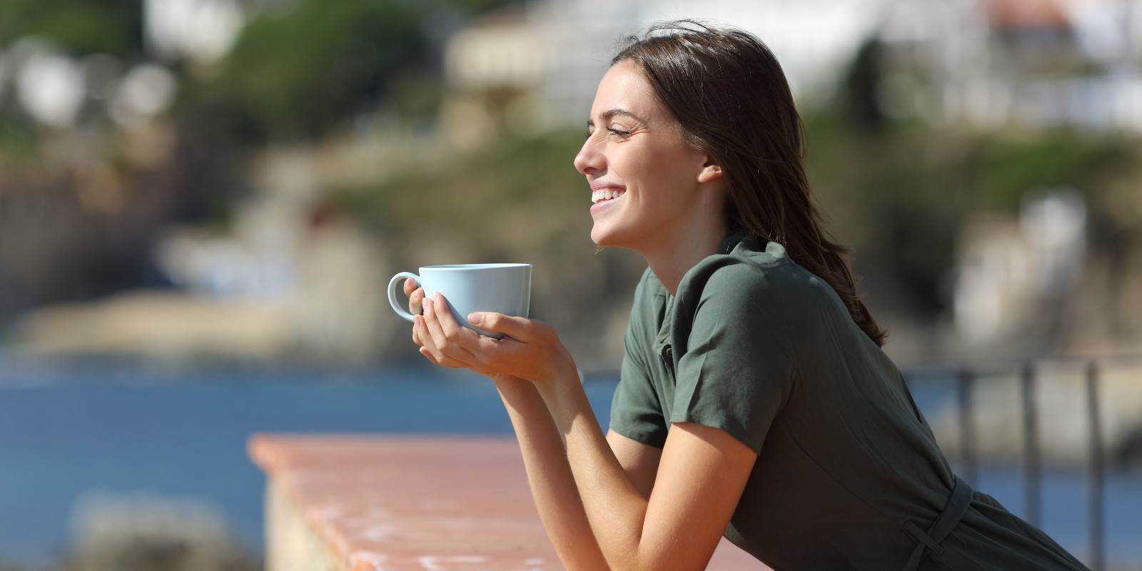 Eine junge Frau lehnt sich über einen Balkon und trinkt Kaffee. Es ist das Titelbild zum Blogbeitrag "Nerven und Psyche" aus komplementärmedizinischer Sicht.