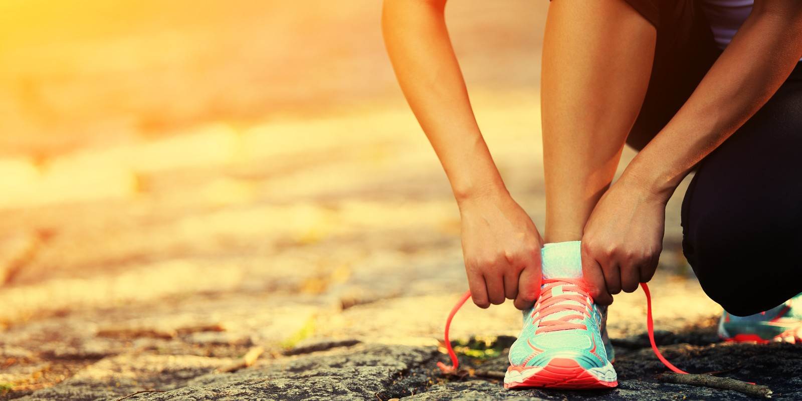 Frau kniet und bindet die Sportschuhe