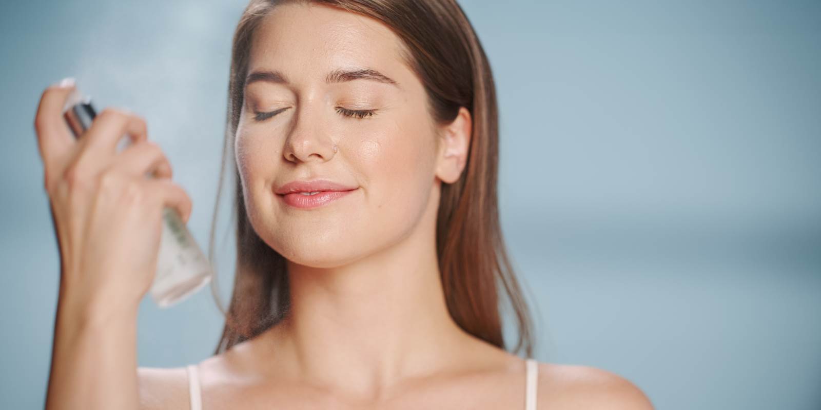Frau sprüht sich ein Hydrolat ins Gesicht