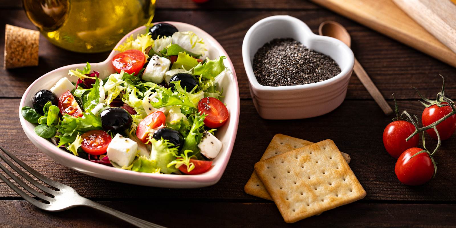 Salat in herzförmigem Teller mit Oliven, Feta, Tomaten und grüner Salat