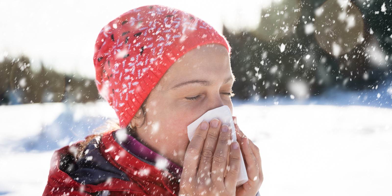 Frau schnäuzt sich im Winter